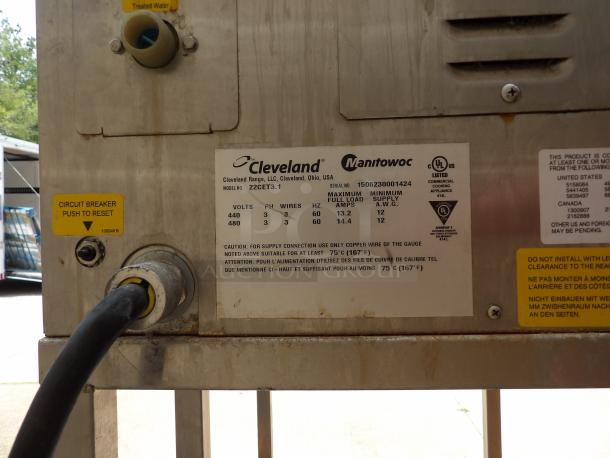 Commercial appliance label, Cleveland Range model 22CET3.1. Displays electrical specs: 440-480V, 60Hz, 13.2-14.4A. Circuit breaker reset tag.