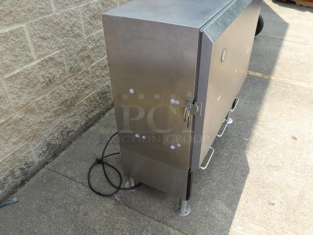 Stainless steel outdoor storage cabinet with four handles, lockable latch, and power cable; minimal wear visible.