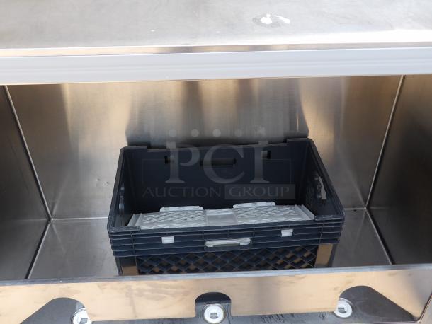 Stainless steel storage unit with a black plastic crate inside, showing a grid pattern and handles. Good condition.