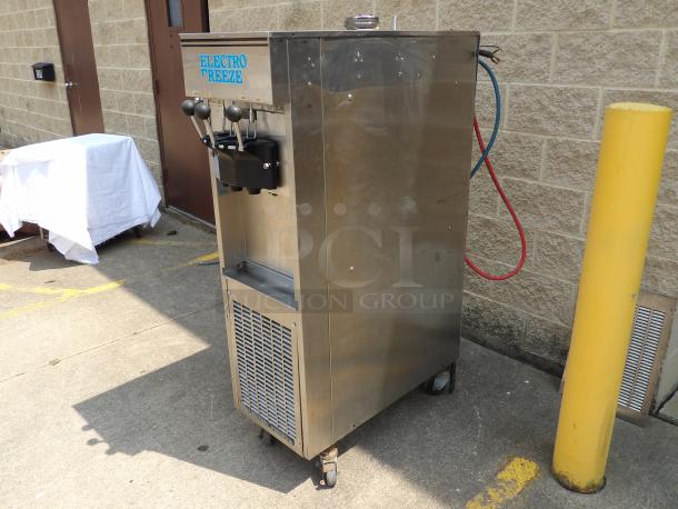 Electro Freeze soft serve ice cream machine, stainless steel, dual handles, model unknown, used condition, mounted on casters.