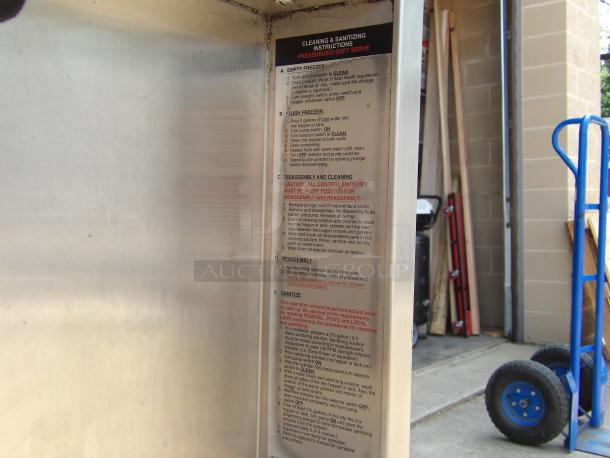 Commercial soft serve machine with cleaning instructions panel. Stainless steel exterior, good condition. Ideal for restaurants.