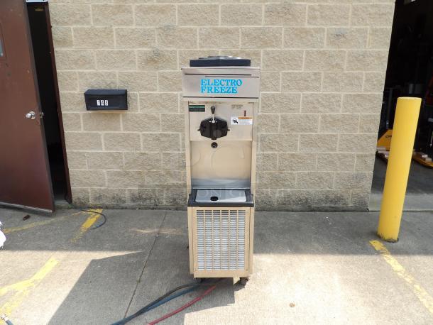 Electro Freeze soft serve machine, stainless steel, used, model details unspecified, front dispensing lever, visible wear.