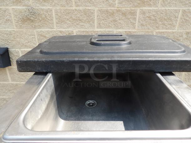 Stainless steel deep sink with a weathered black plastic lid, suitable for commercial use.