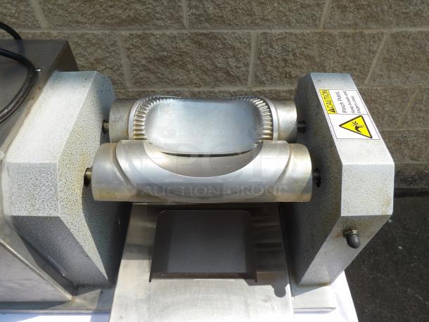 Commercial dough sheeter in used condition, featuring metal rollers and safety caution label. Suitable for pastry preparation.