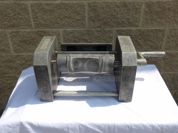 Industrial metal roller press, sturdy construction, used condition. Features a manual handle and gear details. No visible labels.