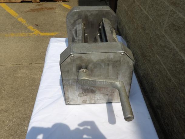 Metal hand-cranked machine on a white cloth. Features a large handle and sturdy construction. Slight wear visible.