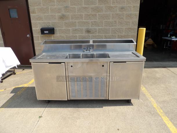 Stainless steel commercial kitchen prep station with double sinks and storage compartments. Used condition.