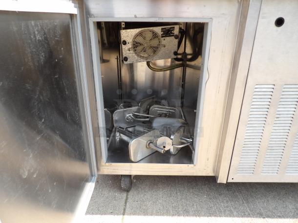 Commercial stainless steel refrigeration unit with open door revealing internal cooling mechanisms. Used condition.