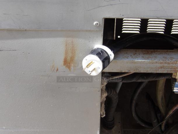 Electrical plug connected to industrial equipment, showing slight rust and wear on metal surfaces. Plug in good condition.