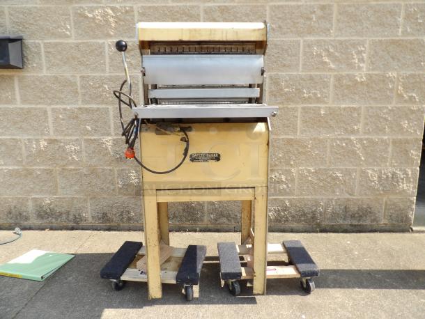 Vintage Safety-Slicer machine on wheels, with a metal slicer mechanism. Appears used, with a yellow body and lever.