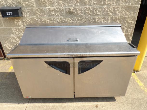 Stainless steel commercial refrigerator with dual doors and a top sliding lid. Slight surface wear visible.