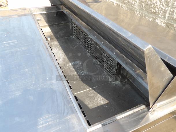 Stainless steel commercial charbroiler, open lid showing grilling area, some wear visible, no labels or markings.