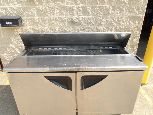 Commercial stainless steel refrigerated prep table, two-door, with hinged cover and internal racks, in used condition.
