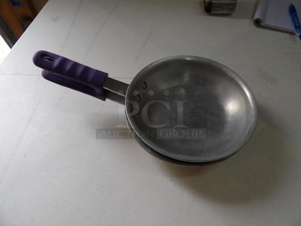 Small metal frying pan with a purple silicone handle. Lightly used, showing minor surface scratches.