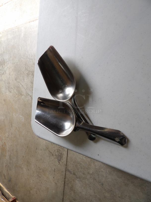 Two stainless steel scoops, medium size, excellent condition, with smooth finish and ergonomic handles, on a light surface.