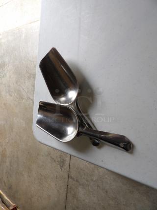 Two stainless steel scoops, medium size, excellent condition, with smooth finish and ergonomic handles, on a light surface.