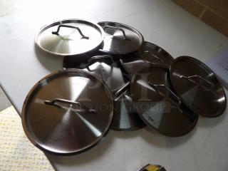 Set of seven stainless steel pot lids with handles, various sizes, good condition, markings indicate size details.