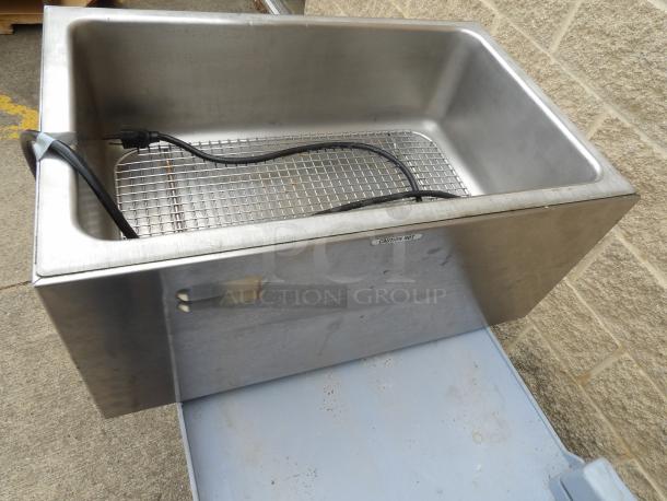 Stainless steel electric food warmer with grid insert and power cord, labeled "Caution Hot," in used condition.