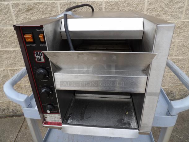 Commercial conveyor toaster by APW Wyott, stainless steel, adjustable heat, used condition, power and temperature controls visible.