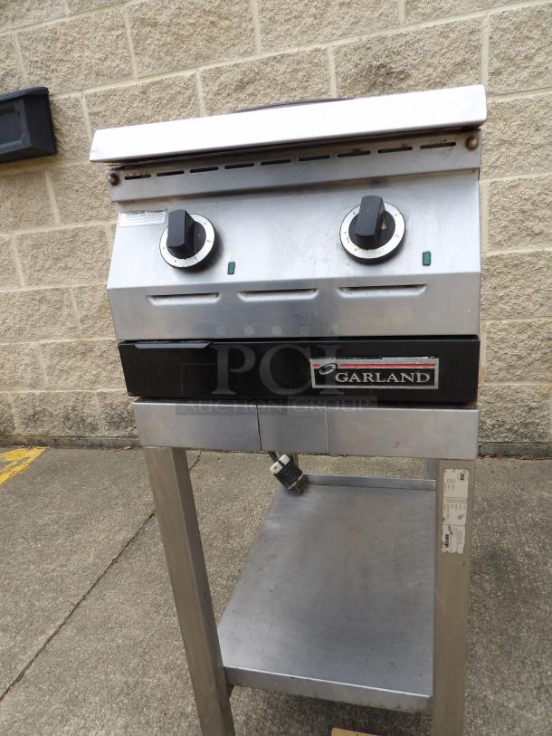 Commercial Garland dual-burner stovetop on a metal stand with visible brand logo, control knobs, and power cord. Good condition.