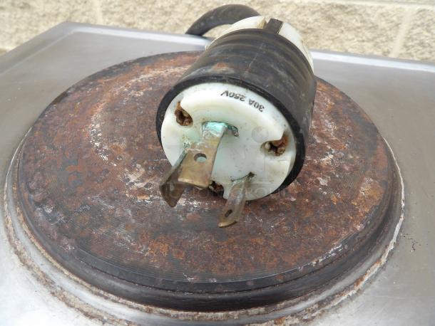 Rusty industrial plug with visible corrosion, labeled "30A 250V," on metal surface, showing wear.