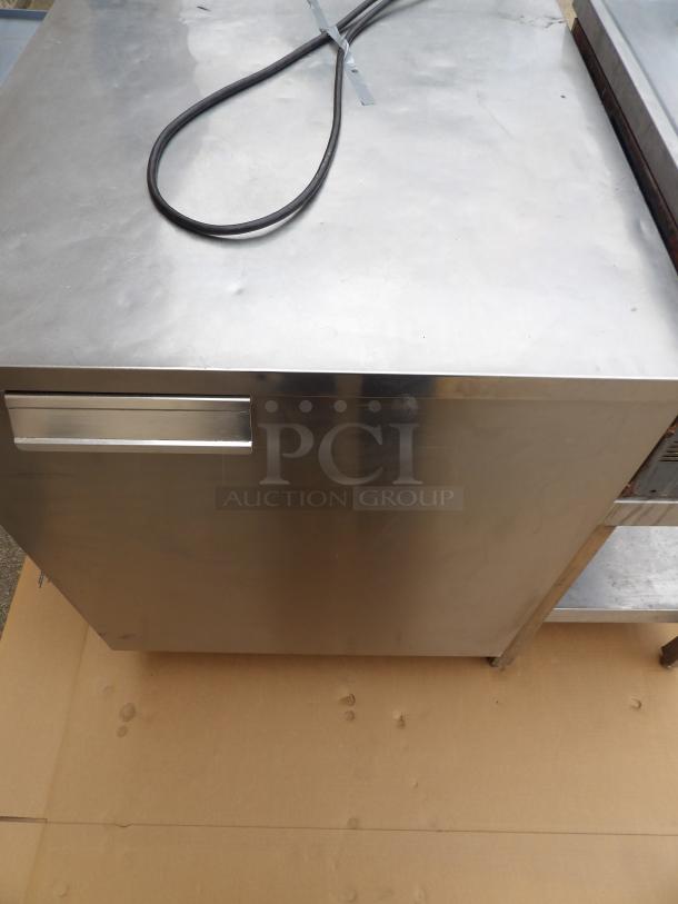 Stainless steel kitchen cabinet, single drawer, visible power cable, minor surface marks, sturdy construction.