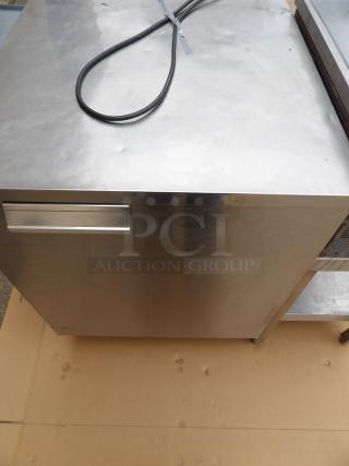 Stainless steel kitchen cabinet, single drawer, visible power cable, minor surface marks, sturdy construction.