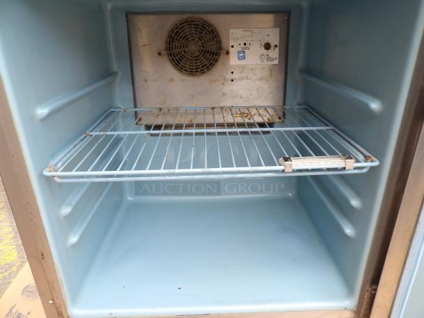Vintage blue refrigerator interior with wire shelf, some rust. Features fan, control panel with labels for cooling options.