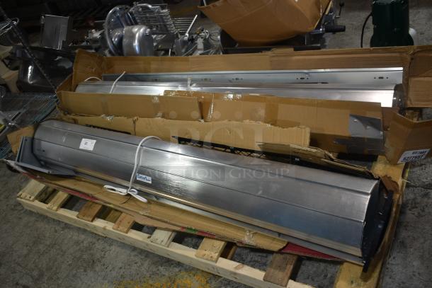 Large stainless steel industrial air curtain in cardboard packaging, model sticker visible, on wooden pallet.