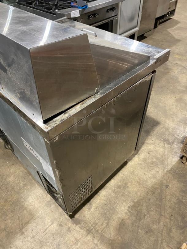 Stainless steel commercial refrigerated prep table with dual compartments, visible wear and scratch marks.