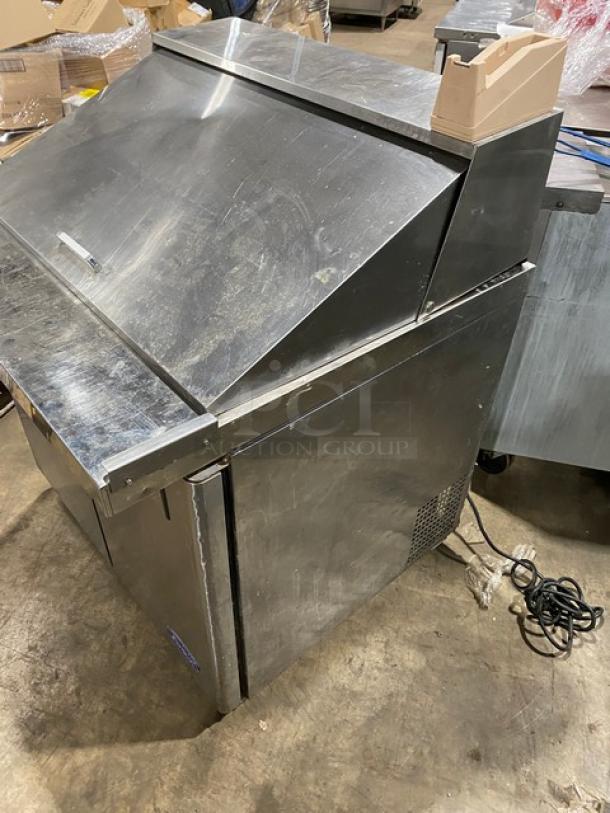 Commercial stainless steel food prep station with top access lid, storage compartment, and visible wear. Power cord included.
