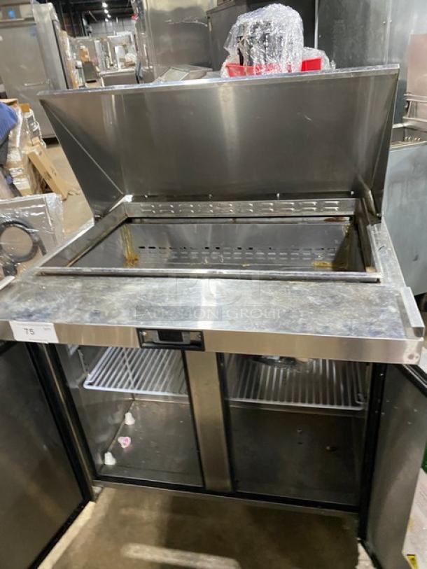 Commercial stainless steel refrigeration unit with top lid open and double-door storage; moderate wear visible; item number 75.