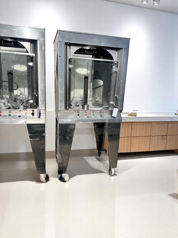 Commercial vertical rotisserie machine, stainless steel, on wheels. Features temperature control knobs, labeled "Caution Hot."
