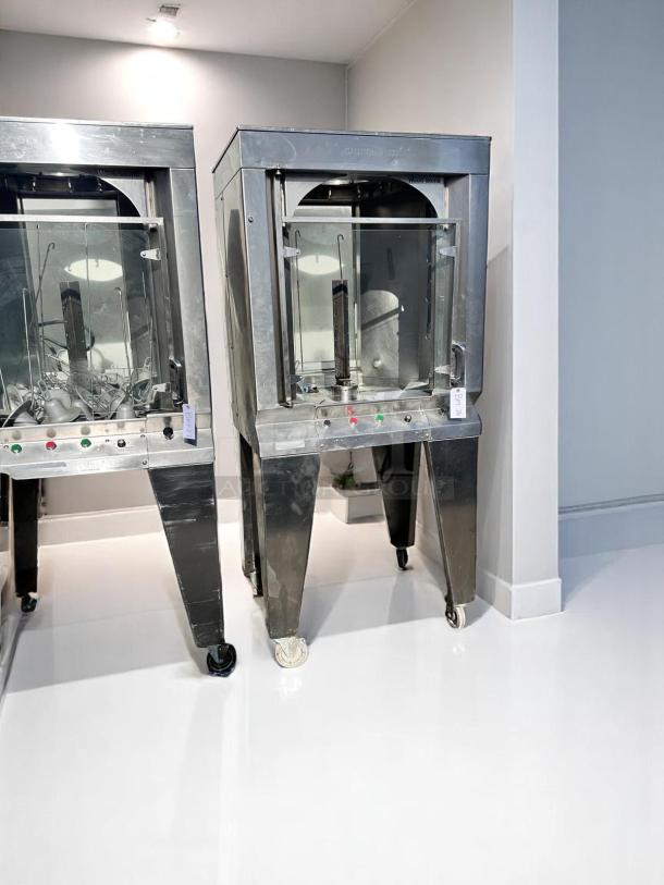 Stainless steel commercial rotisserie oven, glass front, control panel with buttons, on wheels, excellent condition.