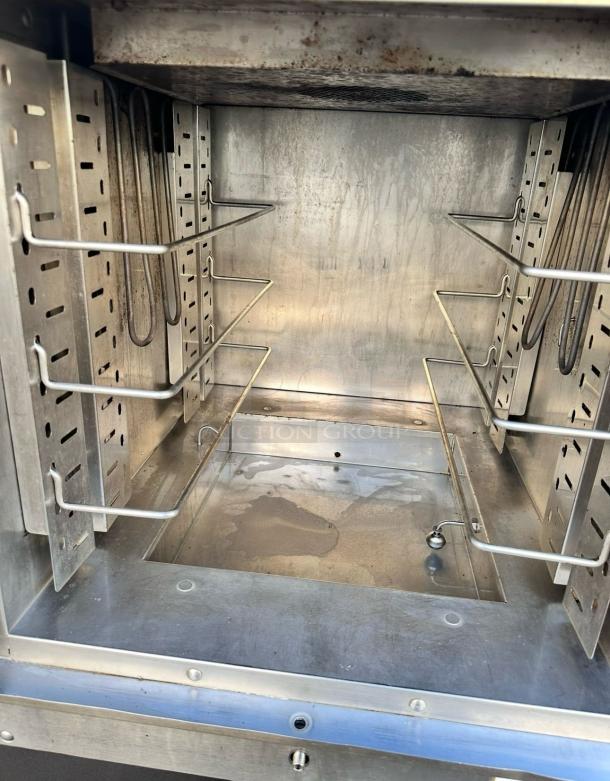 Commercial stainless steel oven interior with adjustable shelving. Slight wear, showing heating elements and pan insert.