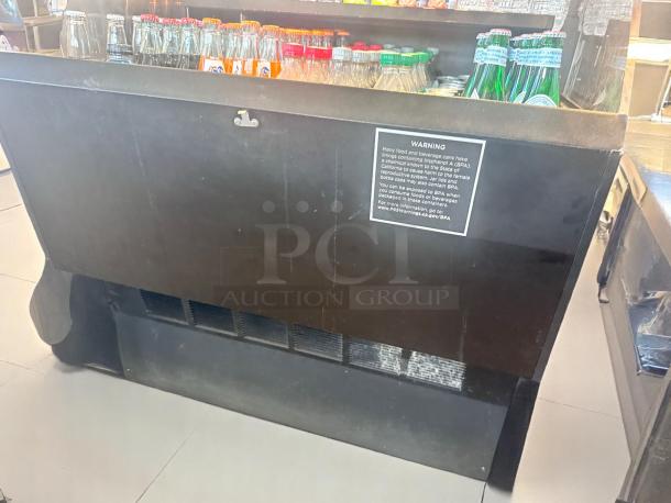 Black beverage cooler with visible warning label about BPA exposure. Contains assorted bottled drinks. Sturdy, used condition.