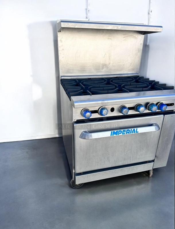 Imperial commercial gas range with 6 burners, stainless steel, blue knobs, good condition. Marked "IMPERIAL" on oven door.