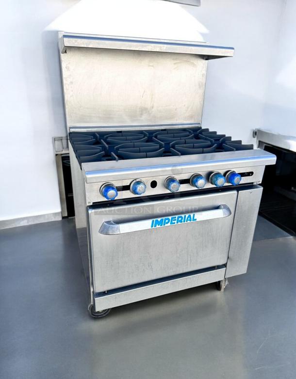 Imperial stainless steel commercial gas range with six burners and oven. Features blue control knobs, in excellent condition.