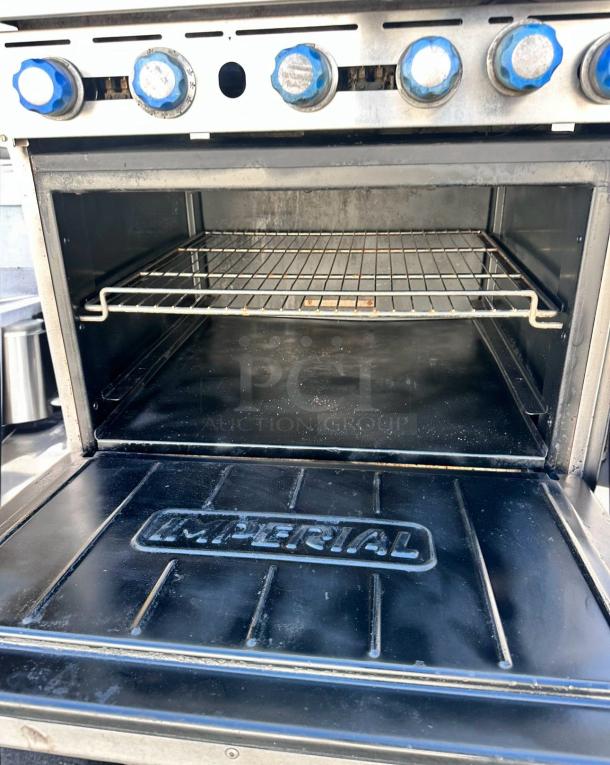 Commercial oven with five blue knobs and wire rack, brand "Imperial" embossed on front. Slight signs of use, good condition.