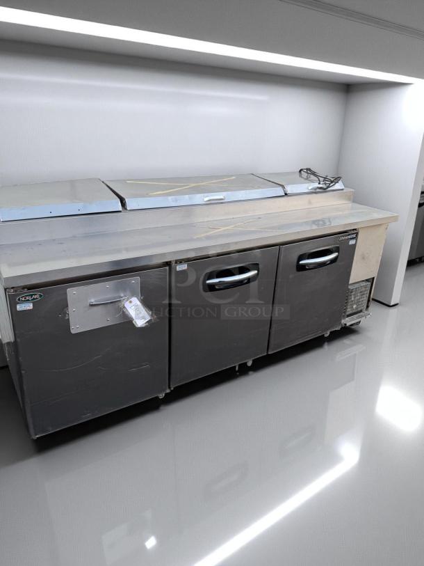 Stainless steel commercial refrigerator unit with dual doors, Norlake brand. Features switch and control panel. Good condition.