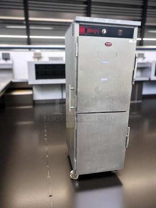 Stainless steel FWE heated holding cabinet with dual doors, control panel, and casters. Used condition with visible markings.