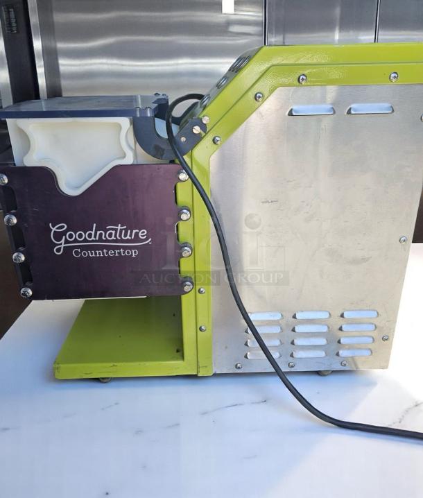 Goodnature Countertop juicer, stainless steel and green finish, visible power cord, high-quality condition, ideal for cafes.