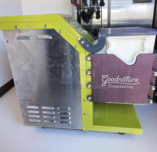 Goodnature countertop juice press, stainless steel and green finish, visible used condition, brand logo on side panel.