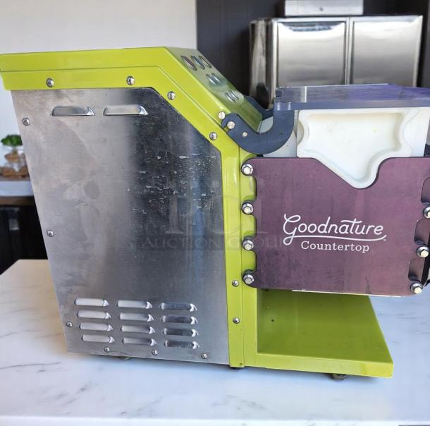 Goodnature Countertop juicer in green and stainless steel, features visible branding, used condition with some wear marks.