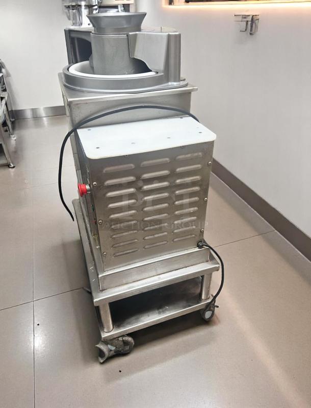 Commercial stainless steel food processor, used condition, featuring robust design, mounted on wheels for mobility.