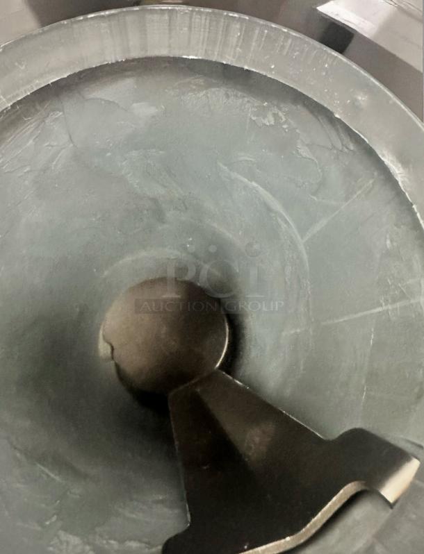 Industrial mixing bowl with internal paddle, stainless steel, used condition, visible wear and scratches on surface.