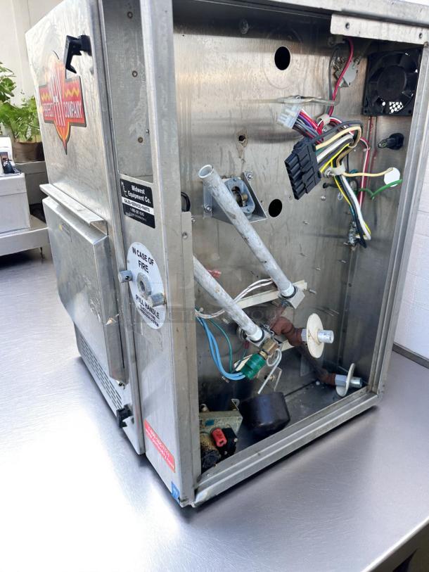 Industrial popcorn machine, Midwest Equipment Co. branding, visible internal wiring and components, used condition, fire safety label.