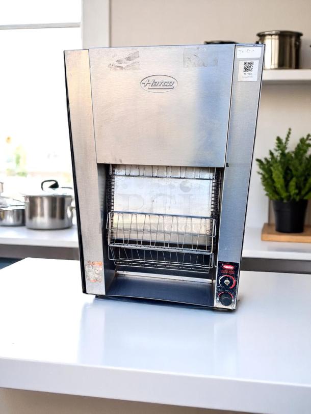 Hatco commercial toaster, stainless steel, vertical conveyor design, with control dials. Visible brand logo. Used condition.