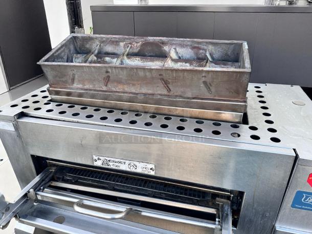 Industrial stainless steel conveyor toaster with heavy-duty metal bread pan. Used condition, caution hot label visible.