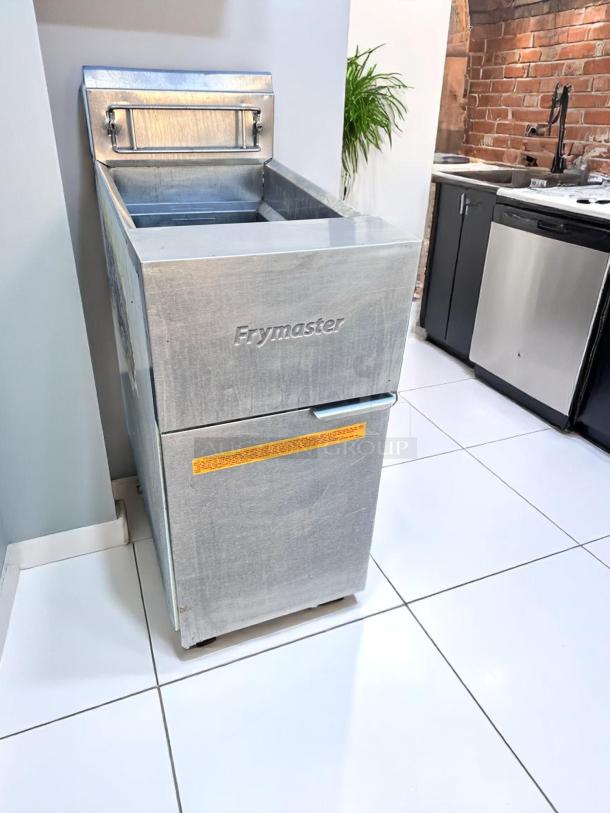 Frymaster deep fryer in stainless steel, used condition, visible brand marking, orange safety label on door, suitable for commercial use.